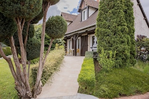A house with a paved driveway, a front door, and a small patio area.