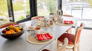 A dining table set with various dishes, a bowl of fruit, and a view of the outdoors.