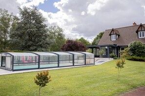 A house with a swimming pool covered by a glass structure, a garden with small trees, and a large tree in the background. - Le Clos 'Majanpie' with Private Pool, Wi-Fi, and Air Conditioning (Meusnes)
