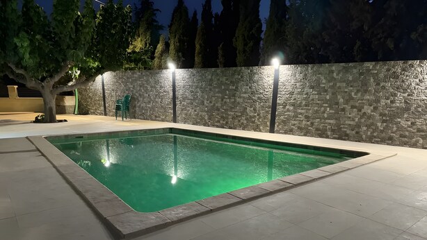 A rectangular swimming pool with a stone wall and a tree in the background. - Rural House 'Casa Bartolo' with Mountain Views, Wi-Fi and Air Conditioning (Vélez-Rubio)