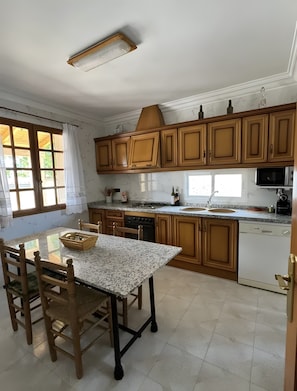 Una cocina con armarios de madera, encimera de granito, una mesa de comedor con sillas y un horno empotrado.