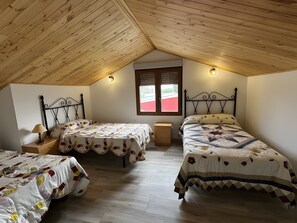 A room with two beds, a window, and a wooden ceiling.