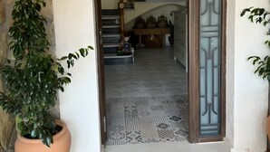 A stone wall entrance with a wooden door, a potted plant, and a patterned mat. - Rural House 'Casa Bartolo' with Mountain Views, Wi-Fi and Air Conditioning (Vélez-Rubio)