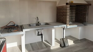 A kitchen with a built-in brick oven, stainless steel sink, and a hose connected to a machine. - Rural House 'Casa Bartolo' with Mountain Views, Wi-Fi and Air Conditioning (Vélez-Rubio)