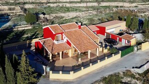 A residential property with a red and yellow facade, a covered patio, and a driveway. - Rural House 'Casa Bartolo' with Mountain Views, Wi-Fi and Air Conditioning (Vélez-Rubio)