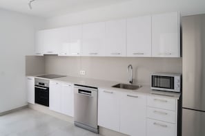 A modern kitchen with white cabinetry, stainless steel appliances, and a dishwasher. - Ereza Villas La Granja (Yaiza)