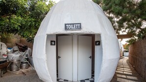 Un baño portátil con un letrero que dice 'TOILETT' y un piso con estampado de cuadros.