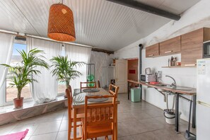 Une cuisine avec des meubles de rangement en bois, un évier et un coin repas comprenant une table et des chaises.