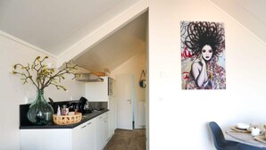 Eine moderne Küche mit weißen Schränken, ein Essbereich mit einem blauen Stuhl und einem an der Wand hängenden Gemälde.
