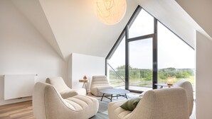 A modern interior with a high ceiling, large windows, and a view of the outdoors. - Les Dunes de Pors Carn – 3 Bedrooms, Panoramic Sea View, 100m from the Beach (Penmarch)