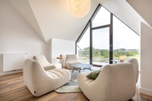 Um interior moderno com teto alto, janelas amplas e vista para o exterior.