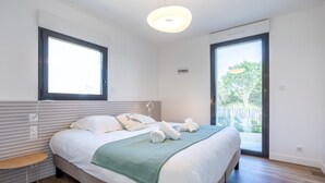 A modern bedroom with a bed, bedside table, and a view through a sliding glass door.