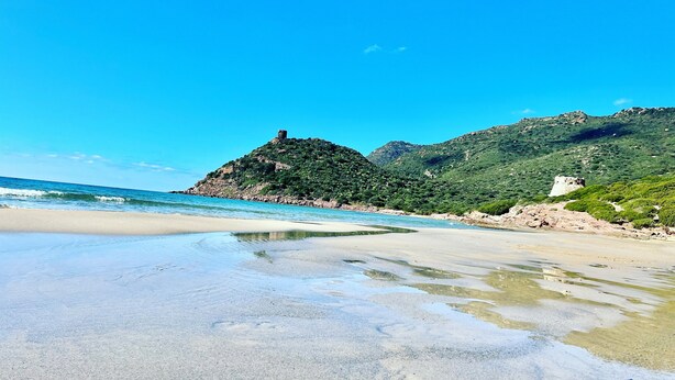 A beach with clear water, a sandy shore, and green hills in the background. - Holiday Home 'Apartment For 6 People Near The Sea' with Balcony, Wi-Fi and Air Conditioning (Alghero)