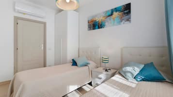 Ein Hotelzimmer mit zwei Betten, einem Nachttisch mit Lampe, einem Bild an der Wand und einer Klimaanlage.