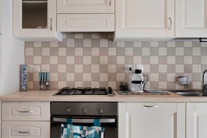 Una cocina con estufa a gas, cafetera y lavaplatos.