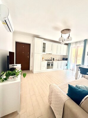 Eine moderne Wohnung mit Küchenzeile, Essbereich und Wohnzimmer mit Bett.