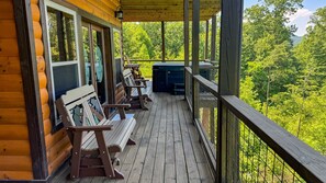 Eine Holzterrasse mit Bänken und einem Whirlpool mit Blick auf ein bewaldetes Gebiet.