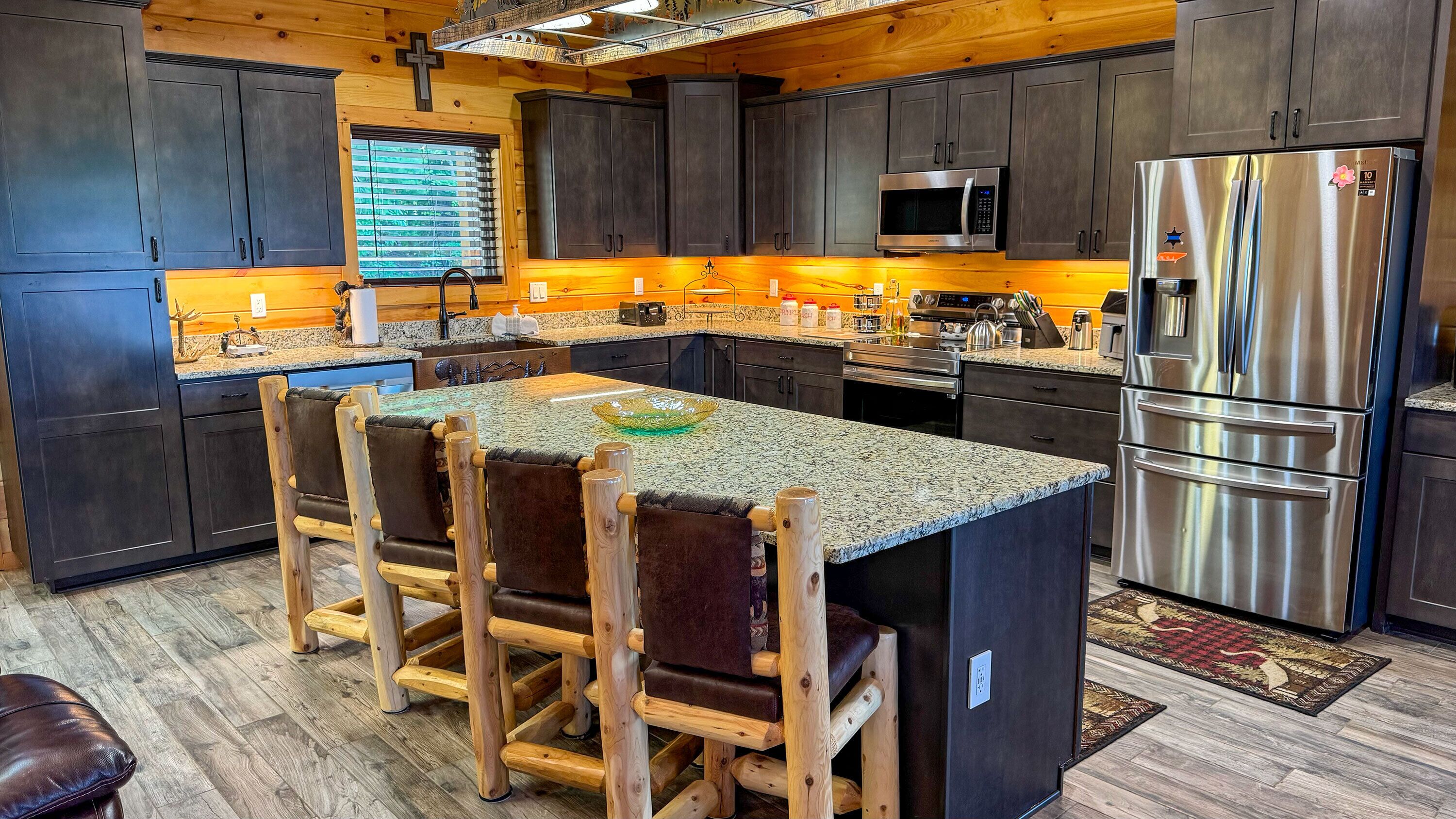 A modern kitchen with dark wood cabinets, stainless steel appliances, and a central island with seating.