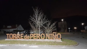 A sign with 'TORRE de PERONINO' in large letters, surrounded by a grassy area and a few trees.
