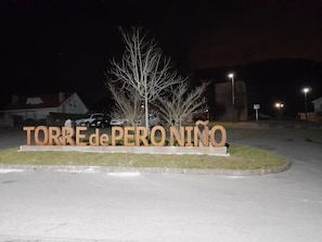 A sign with 'TORRE de PERONINO' in large letters, surrounded by a grassy area and a few trees.