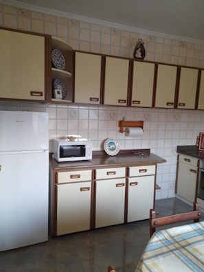 Eine Küche mit Kühlschrank, Mikrowelle und Holzausstattung.