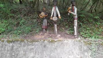 A concrete pathway with three wooden sculptures in a forest setting.