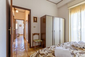 Een hotelkamer met een bed, een kledingkast, een stoel en uitzicht op de gang.