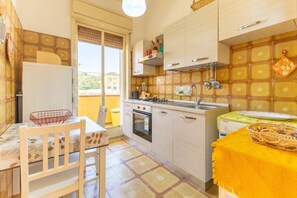Eine kleine Küche mit Essbereich, Kühlschrank, Herd und Spüle.