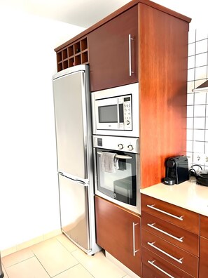 Una cocina equipada con refrigerador, microondas, horno y cafetera.