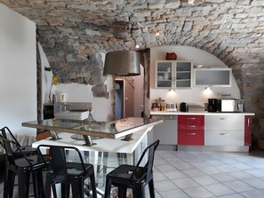 Een keuken met stenen muren, een eethoek met stoelen en een modern apparaat.