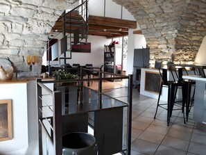 A modern kitchen with a stone arch, a staircase, and a dining area with black chairs.