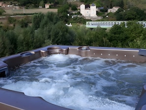 A hot tub with a view of a castle and surrounding greenery.