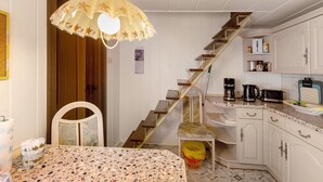 A kitchen with a staircase, a dining table, and a chair.