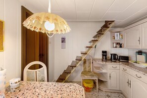 A kitchen with a staircase, a dining table, and a chair.
