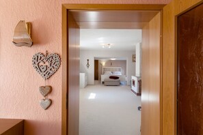 Un pasillo que conduce a un dormitorio con cama, mesita de noche y cómoda.