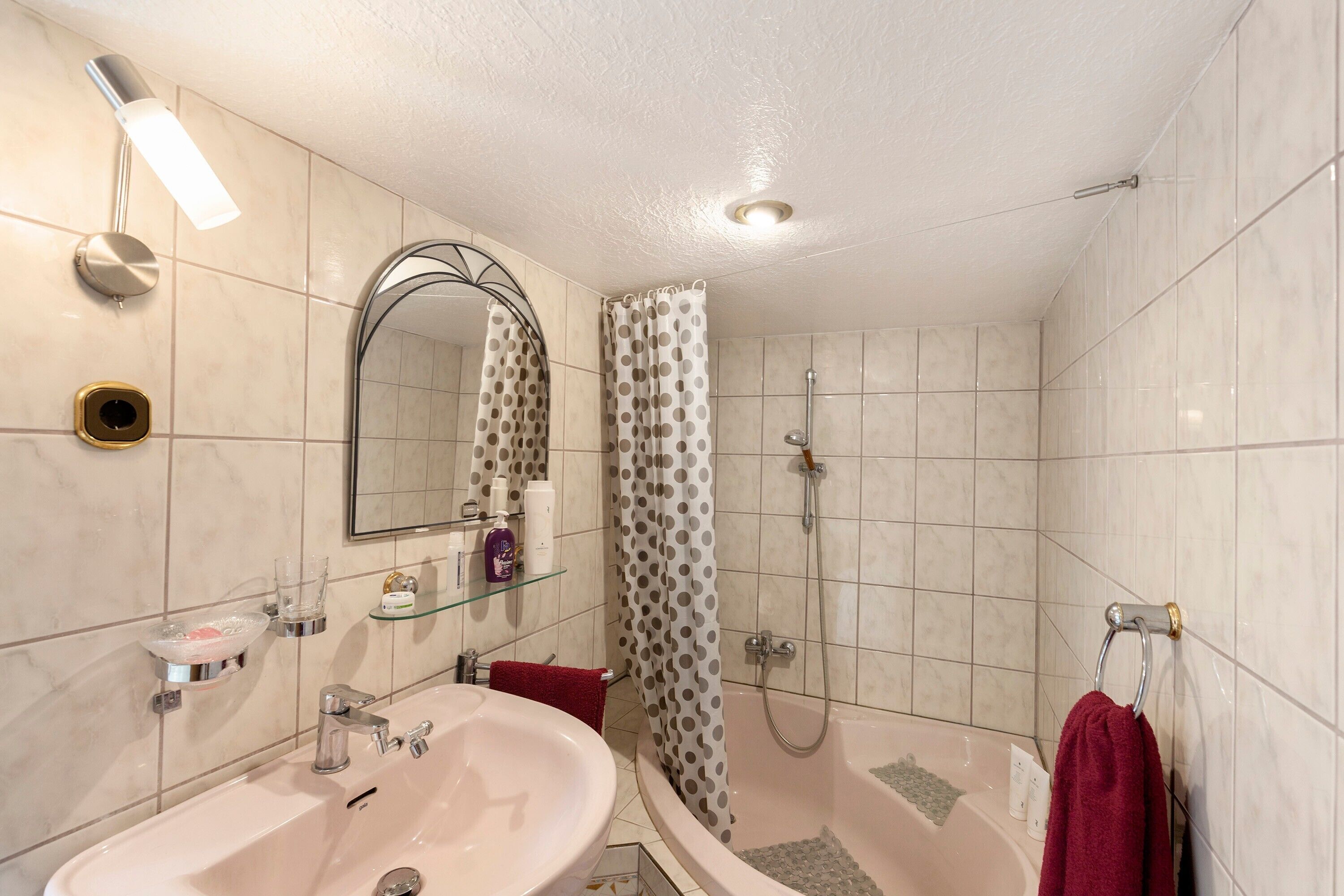 Ein Badezimmer mit Waschbecken, Spiegel, Dusche und Handtuchhalter.