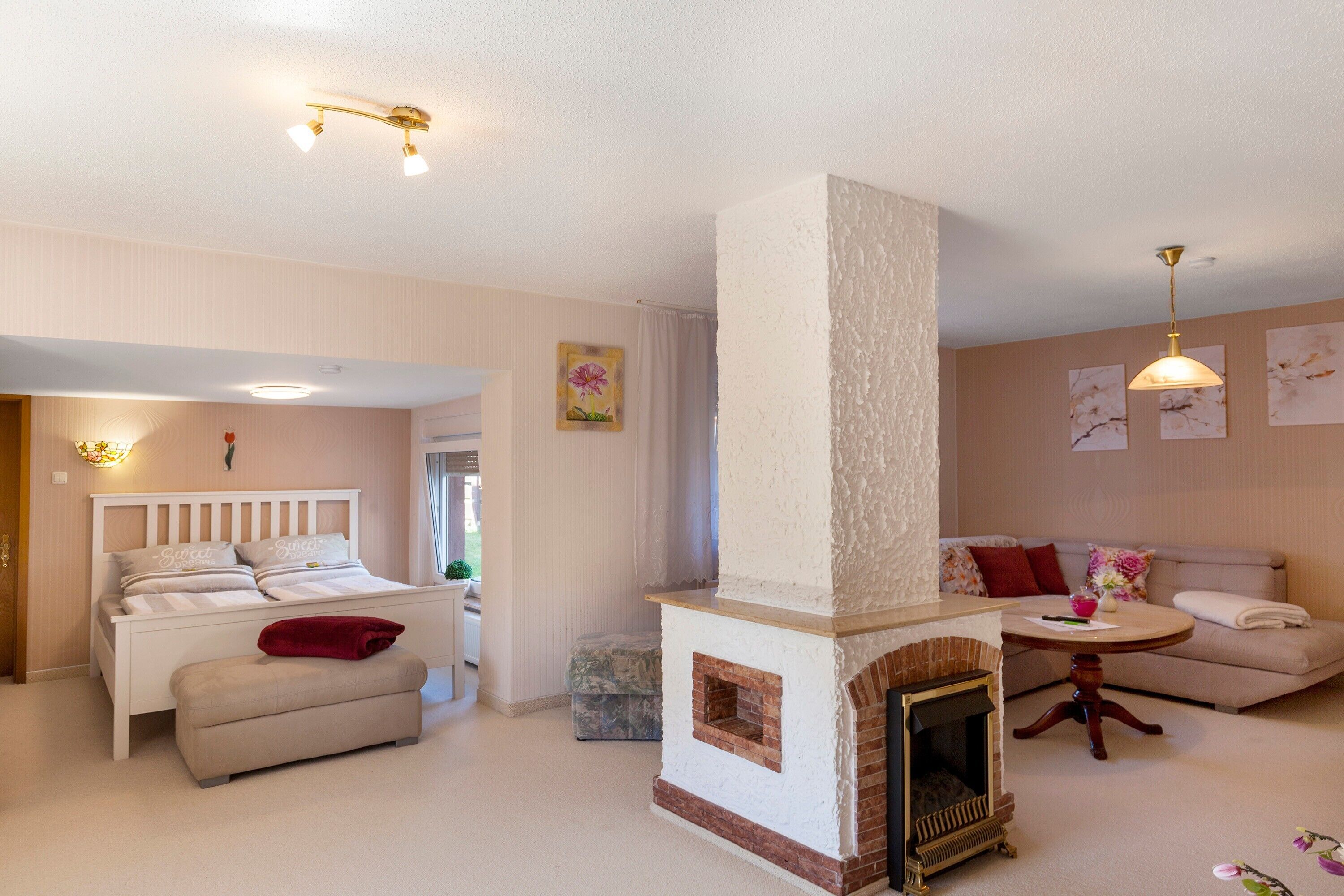 Una habitación acogedora con cama, sofá, chimenea y mesa de comedor.