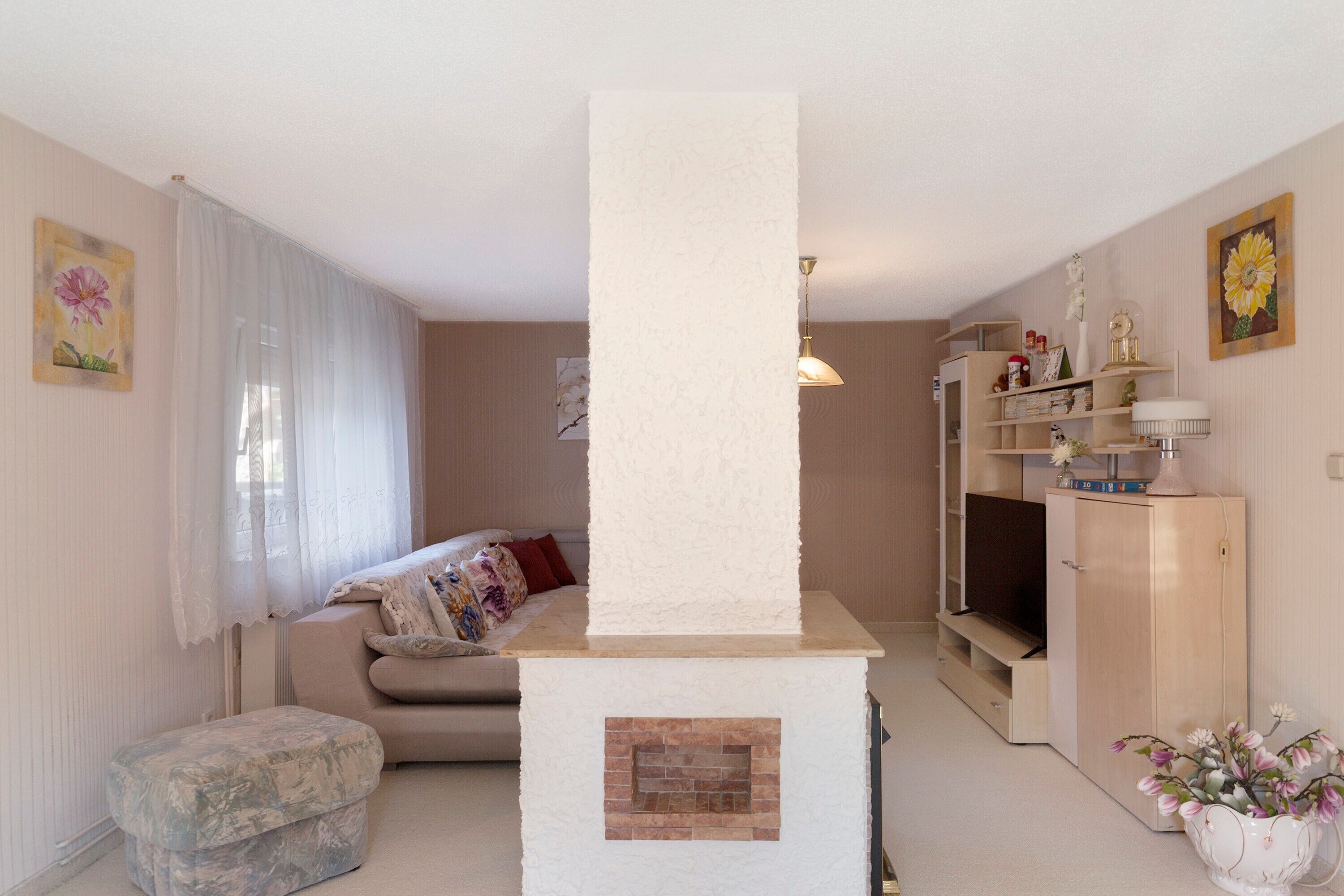 Una sala de estar con sofá, chimenea, televisión y estantería.