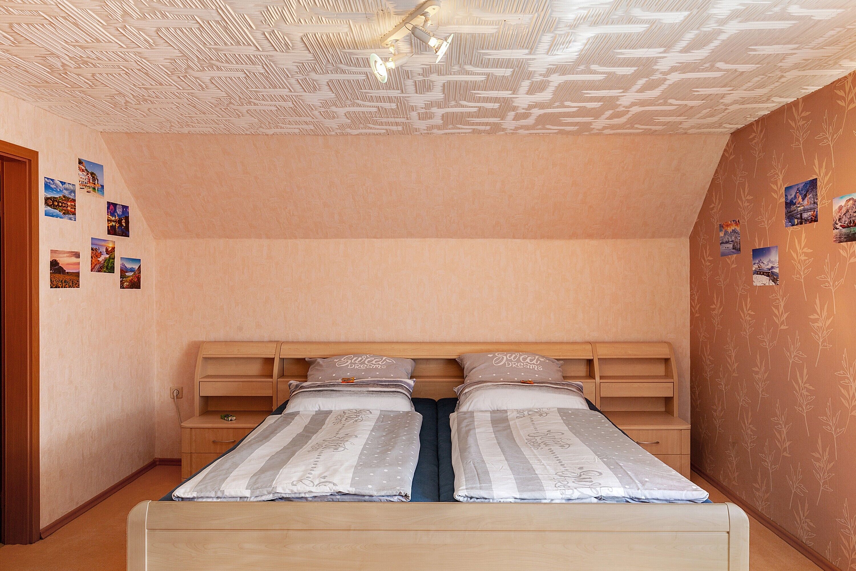 A bedroom with a bunk bed, wooden headboard, and a ceiling with a textured pattern.