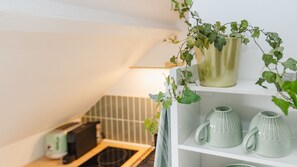 Una estant amb dues tasses de ceràmica i una planta en test.