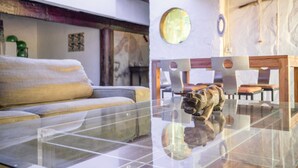 Una sala de estar moderna con una mesa de centro de vidrio, un sofá y un comedor con sillas y una mesa.