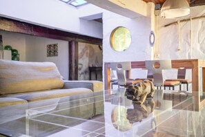 Una sala de estar moderna con una mesa de centro de vidrio, un sofá y un comedor con sillas y una mesa.