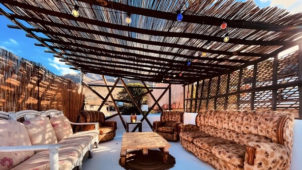 Un área de estar al aire libre con una pérgola, sofás y una mesa de centro.