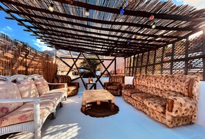 An outdoor seating area with a pergola, sofas, and a coffee table.
