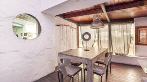 Un comedor con una mesa y sillas de madera, un espejo redondo en la pared y un ventilador de techo.