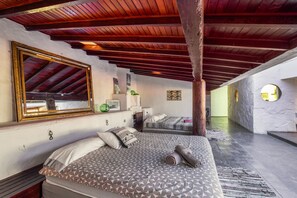 Un dormitorio con una cama grande, un espejo, un escritorio pequeño y vistas al pasillo.