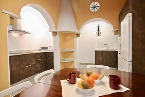 Une cuisine moderne avec des meubles blancs, une table à manger en bois et une horloge au mur.