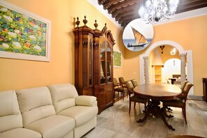A living room with a sofa, a wooden cabinet, a dining table with chairs, and a chandelier. - Apartment 'Siglo Xvii' with Balcony, Wi-Fi and Air Conditioning (El Puerto de Santa María)