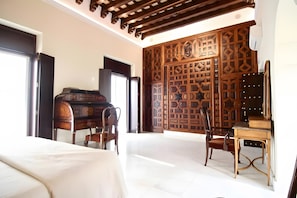 Une chambre à coucher comprenant un lit, deux chaises, un bureau et un paravent décoratif en bois.