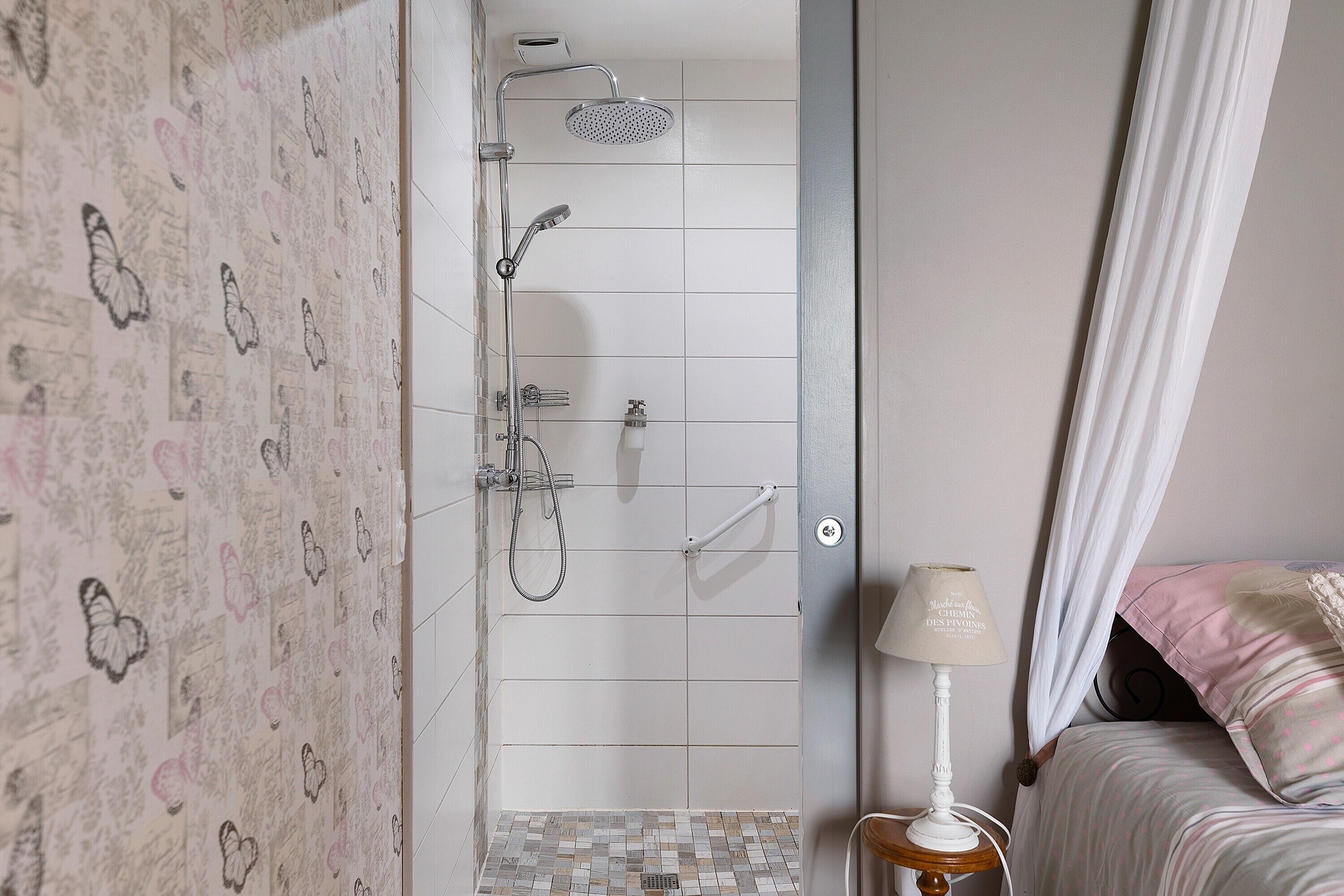 Une salle de bain avec une douche, des toilettes et une table de chevet avec une lampe.
